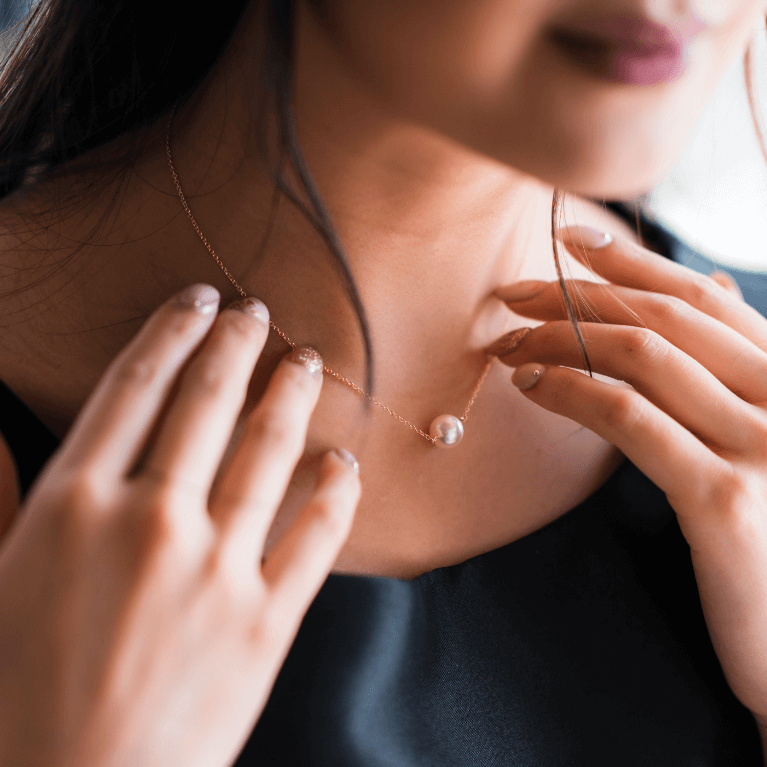 A woman wearing a simple pearl necklace.